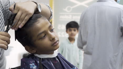 with careful hands at work, a serene young boy sits captivated, his hair being transformed into a stunning masterpiece.