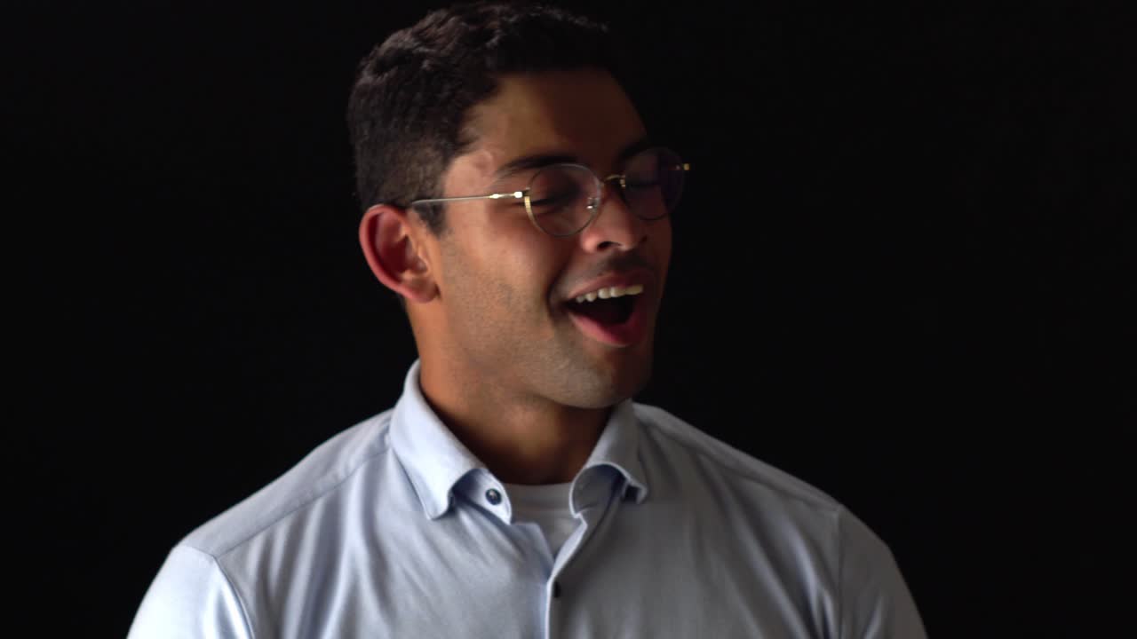 Happy Man In Glasses Smiles At Camera On Black Background
