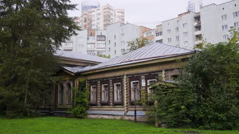 vieja casa de madera en una ciudad con edificios modernos