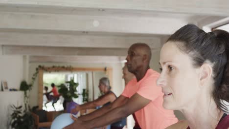 varios ancianos ejercitándose sosteniendo pelotas con una entrenadora de pilates femenina, sin alteración, en cámara lenta