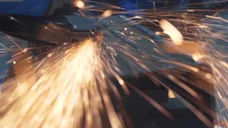 tecnico utilizza una macina a rotazione elettrica per tagliare e macinare materiali metallici di struttura. riparazione meccanica fabbricazione industriale di utensili da girare manuali. scintille luminose scintillanti close-up tiro 4k