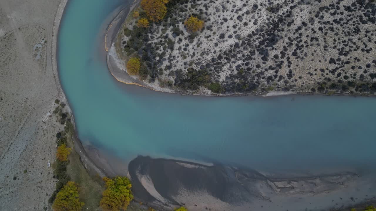 Drone shot of a serene Patagonian river in Argentina, illuminated by soft sunset hues across the plains