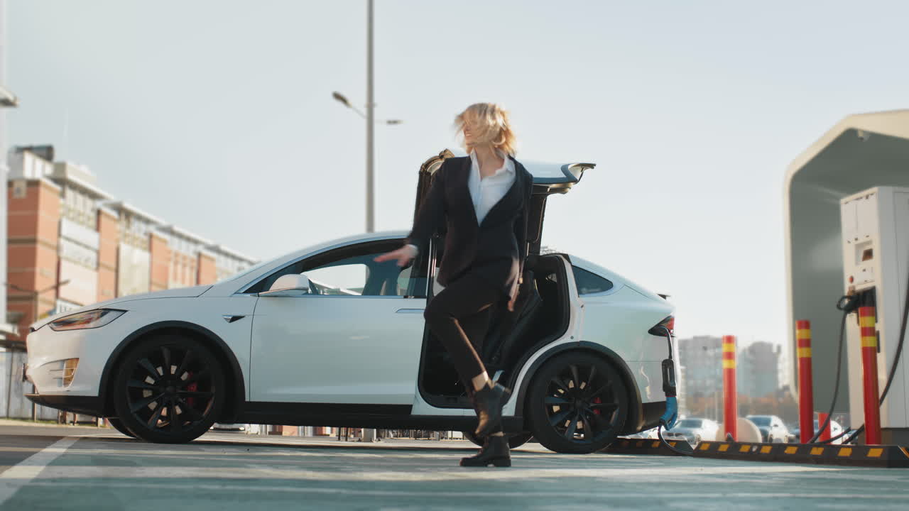 전기 자동차 충전 후 춤을 추는 사업가