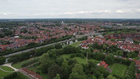 Toma-Aérea-De-Un-Molino-De-Viento-En-Brujas,-Bélgica,-Con-Edificios-Antiguos-Y-Canales.