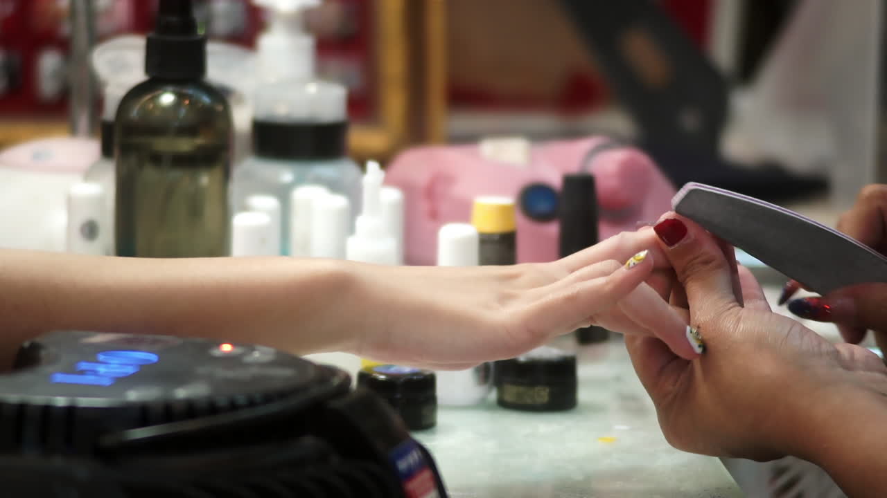Close-up of a woman receiving a professional hand and nail manicure at a beauty salon. Focus on female hands, skincare, and nail care treatment