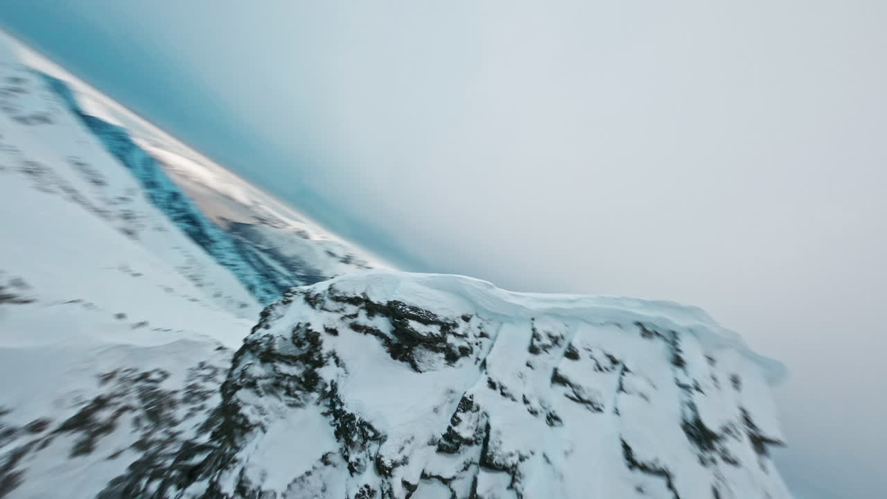 Snow-covered mountain peak in Tromsø fjords under cloudy winter sky