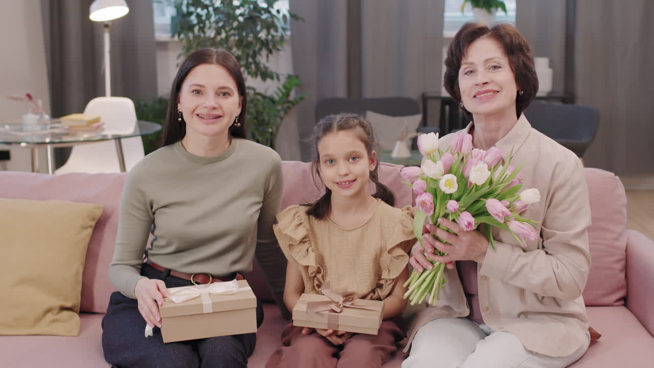 Three generations of women with gifts and flowers