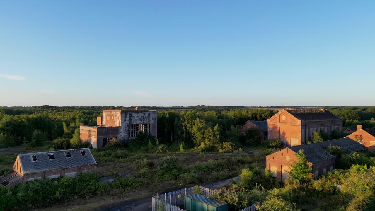 Drone flyver tæt på et overgroet, forladt kulmineanlæg
