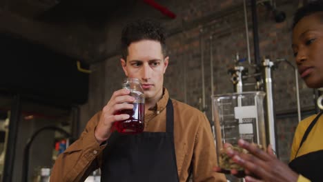 diverse male and female colleague at gin distillery inspecting product ingredients and discussing