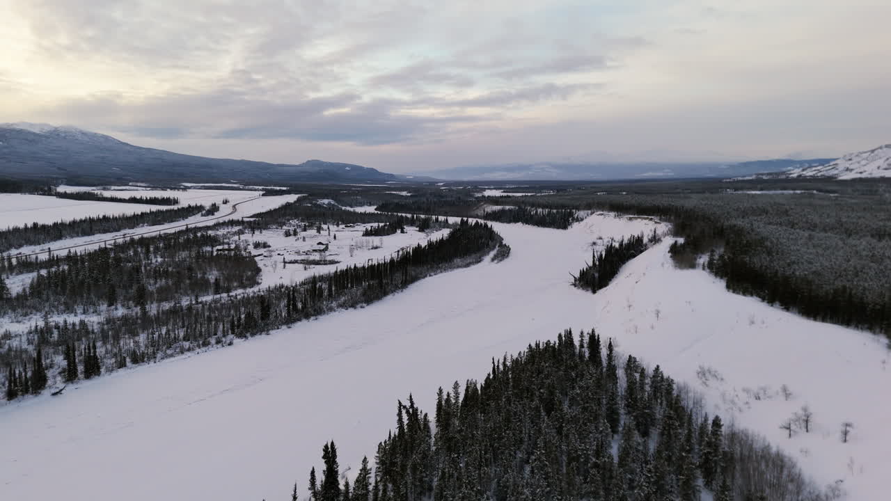 Frozen River And Spruce Forest On Dramatic Sunset In Ibex Valley, Yukon, Canada. aerial shot