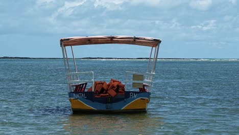 Slow-motion-shot-of-a-small-tourist-transport-boat-docked-on-shore-of-the-Barra-de-Cunhau-beach-in-the-small-coastal-city-of-Canguaretama-near-Natal-in-the-state-of-Rio-Grande-do-Norte,-Brazil