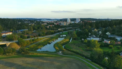 Drone-shot-over-pound,-field-and-railway-in-Upplands-Väsby