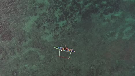 vista aérea de un pescador montando un bote en una playa rosa ubicada en indonesia lombok - toma aérea