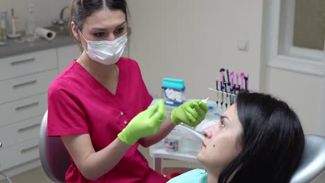 un dentista enmascarado y con guantes explica el próximo tratamiento a su paciente que se prepara para el examen. filmado en 4k