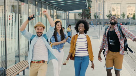 grupo de amigos multiétnicos viajeros divirtiéndose, corriendo y saltando en la estación de autobuses