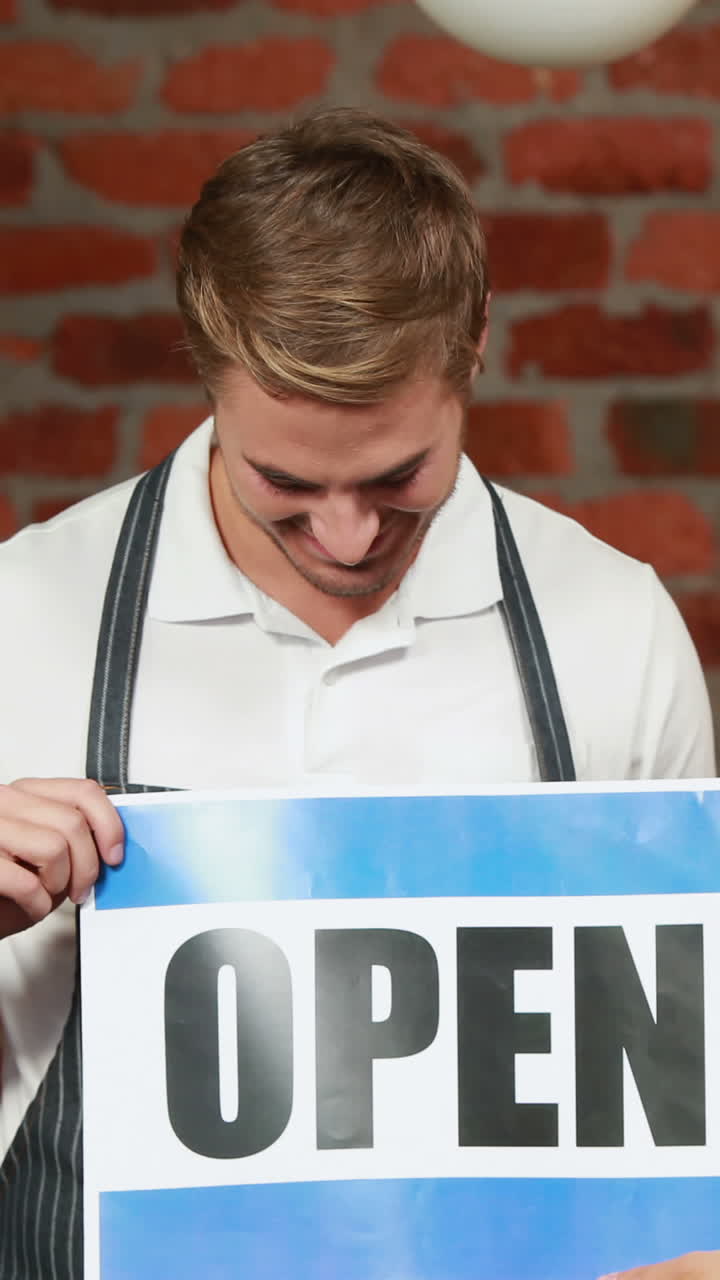 Waiter and customer holding a board with open sign