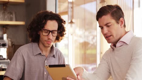 Two-men-using-digital-tablet-in-cafe