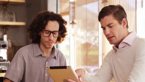 dos hombres usando una tableta digital en un café
