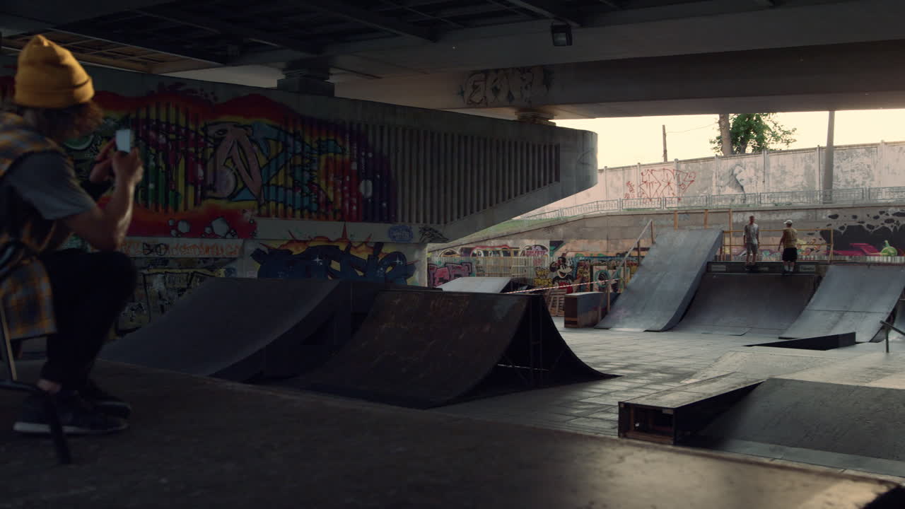 hombre hipster tomando una foto en el teléfono móvil del parque de skate. jinete haciendo video.
