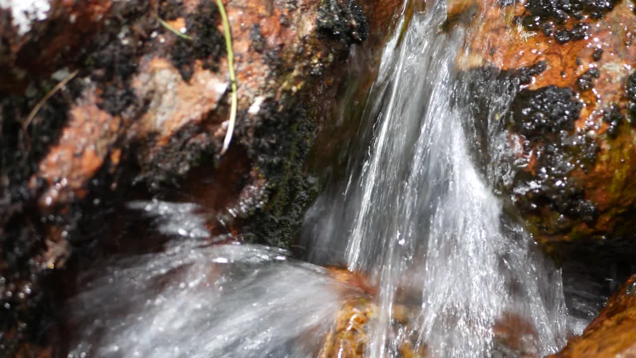 Water cascading over mossy rocks creating a small tranquil waterfall