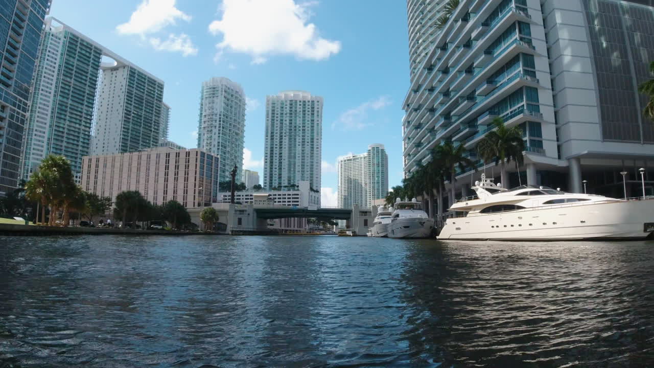 마이애미 플로리다의 해안 수로를 타고 높은 건물과 요트와 함께 이동하는 작은 수상기에서 볼 수 있습니다.