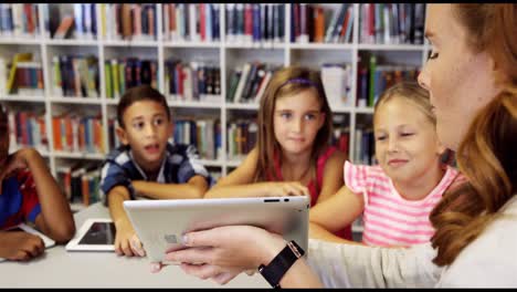 teacher teaching school kids on digital tablet in library