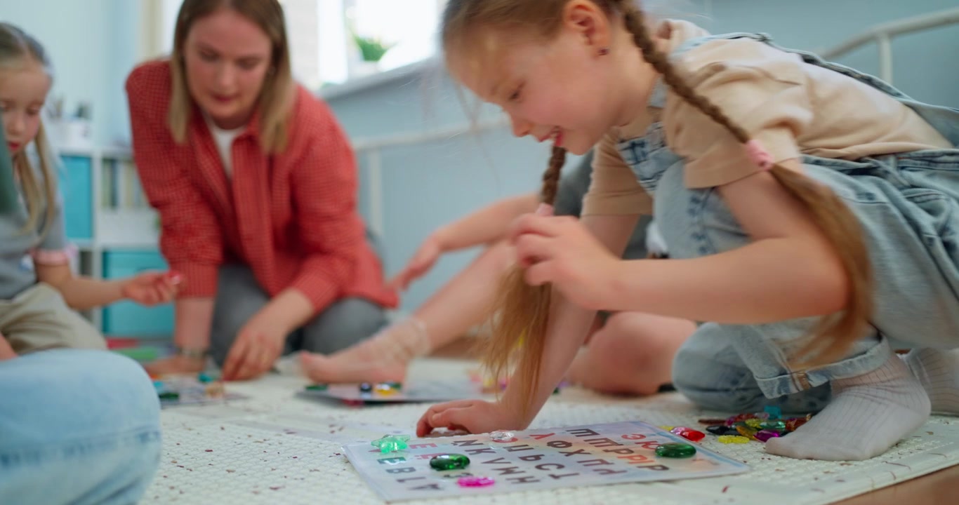 Young Girls and Teacher Engaged in Alphabet Learning Game