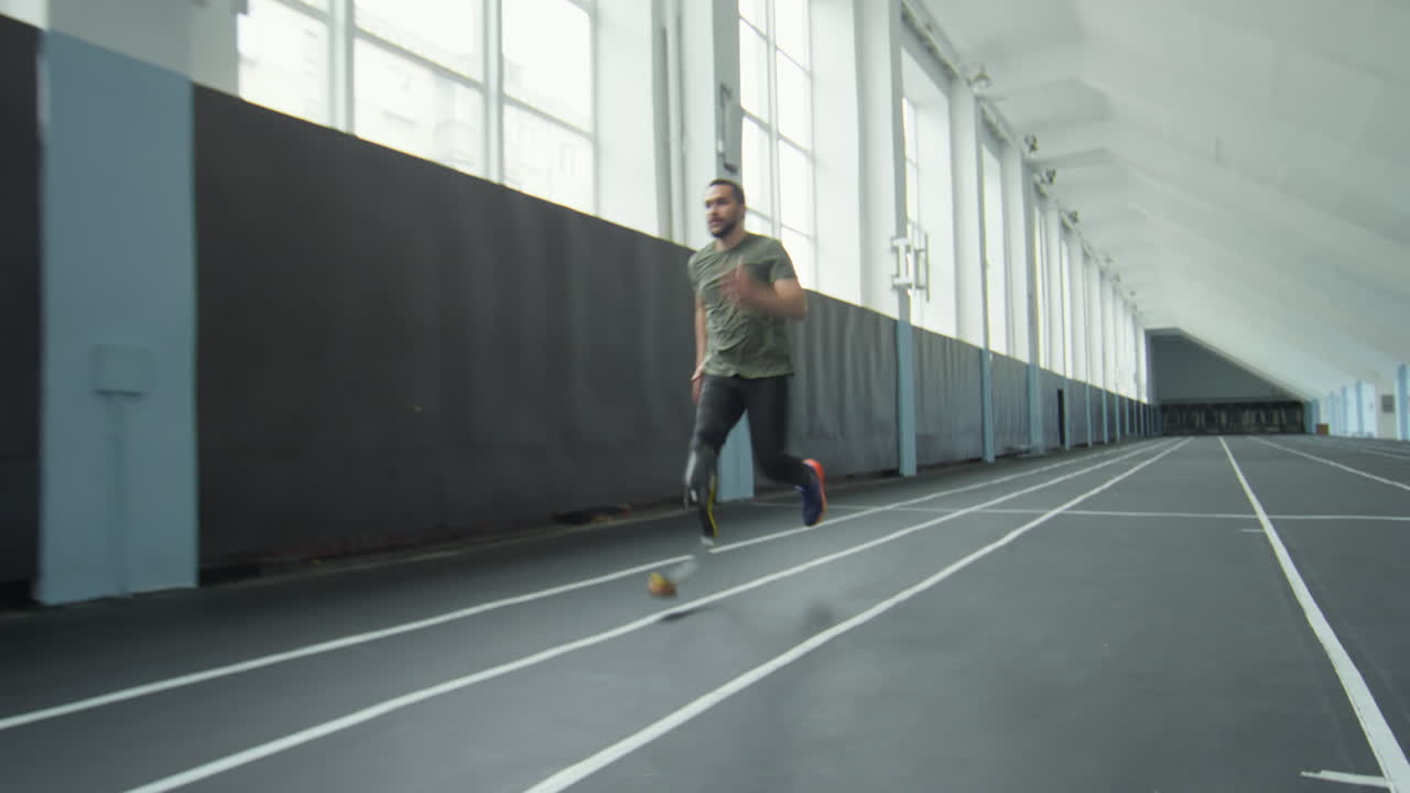 Man with Prosthetic Leg Running in Indoor Stadium