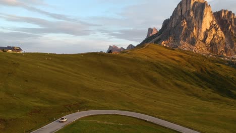 Aufsteigende-Luftaufnahme-Eines-Pickup-Autos,-Das-Zur-Sonnenaufgangszeit-Vom-Bergpass-In-Den-Italienischen-Dolomiten-Herunterfährt