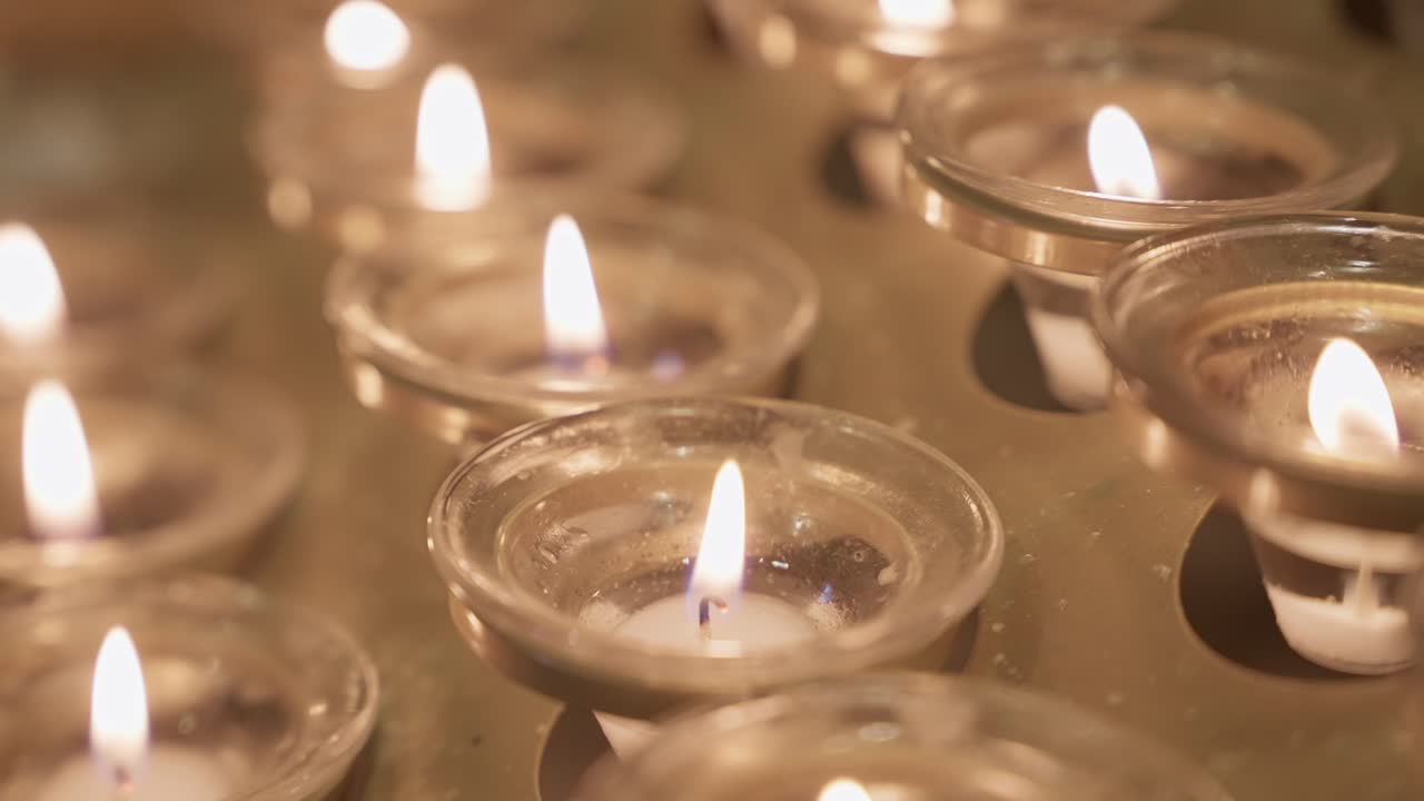 Closeup of lit candles in glass holders inside Christian church