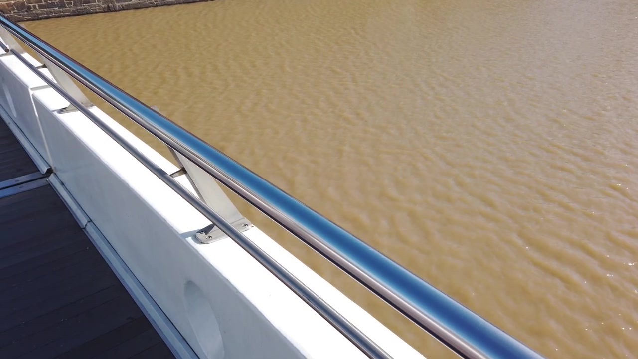 Nahaufnahme des Geländers der Puente de la Mujer mit braunem Wasser des Río de la Plata in Puerto Madero.