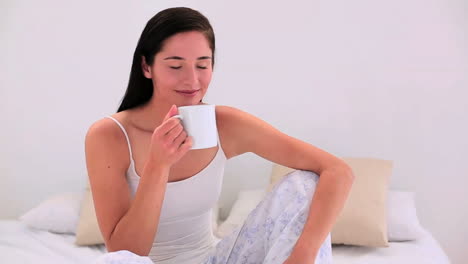 attractive brunette having her morning coffee in bed