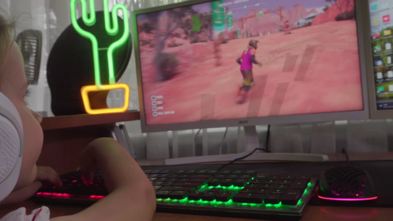 niño pequeño está jugando un juego en una computadora con auriculares blancos en