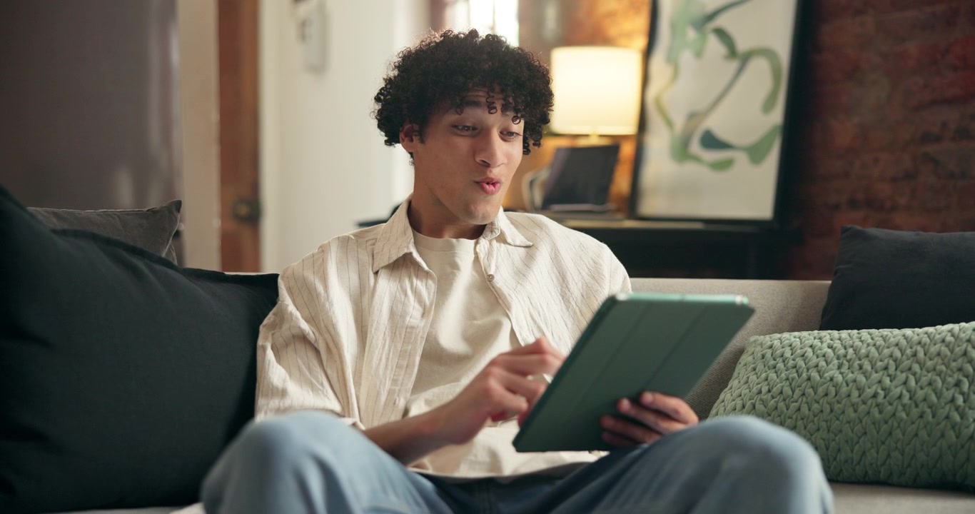 Young Man Using a Digital Tablet on a Sofa at Home