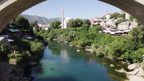 Aerial-fly-under-Stari-Most-Bridge-with-tourist-crowd-in-Mostar,-Bosnia