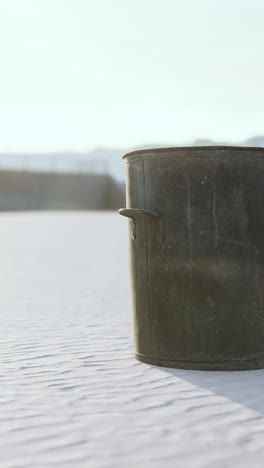 a metal bucket on a beach