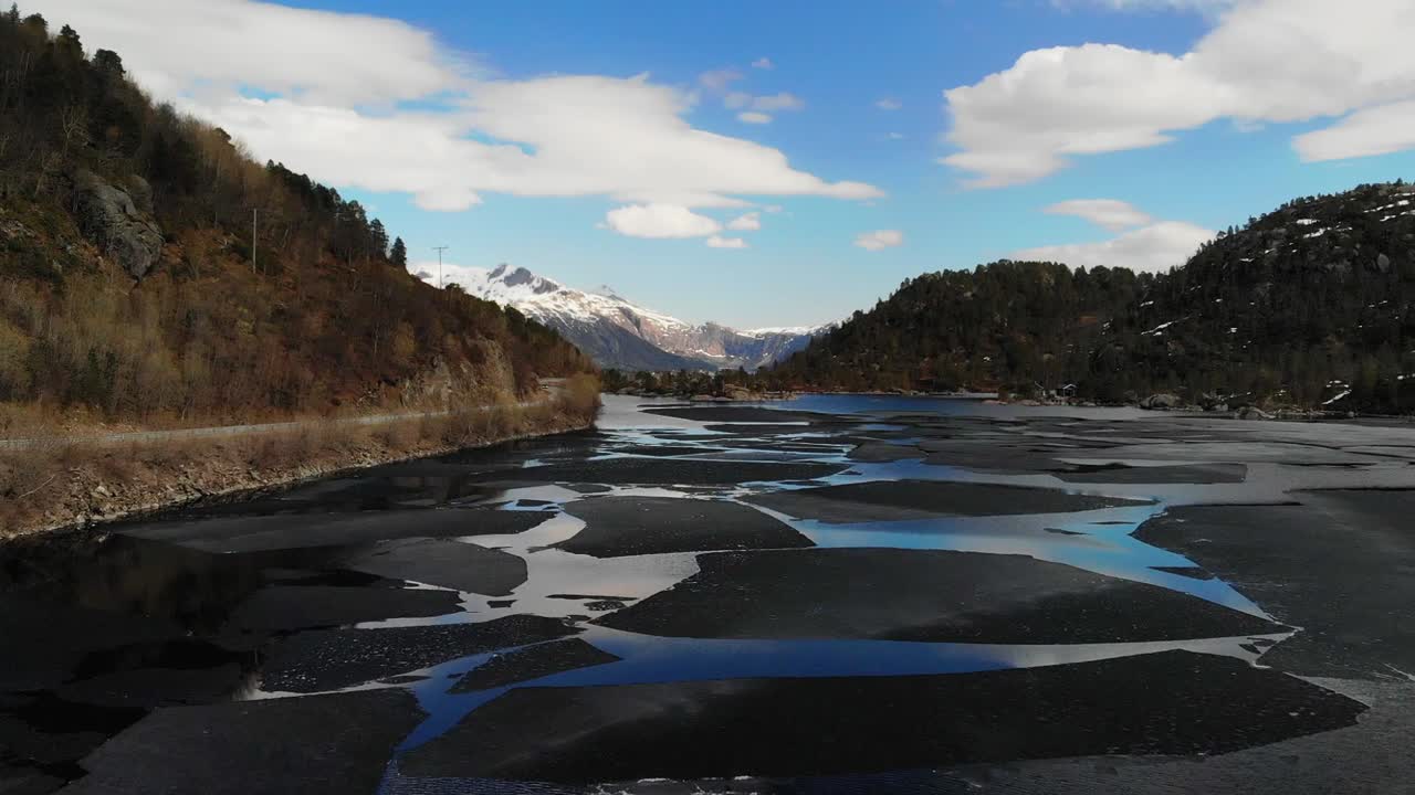 부분적으로 얼어붙은 호수 위로 드론이 솟아올라 아름다운 산악 풍경을 보여줍니다.