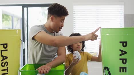 happy biracial man and his son sorting waste in kitchen