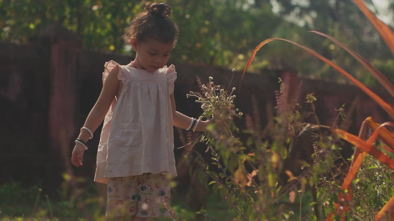 una hermosa joven jugando y divirtiéndose al aire libre en un jardín recogiendo flores en un día soleado