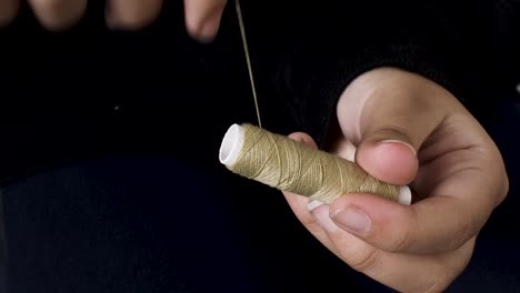 winding light brown sewing thread on spool with both hands