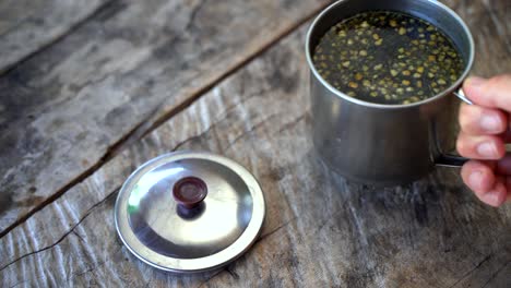 person put down fresh hot guayusa tea on wooden table during travel trip in amazon rainforest