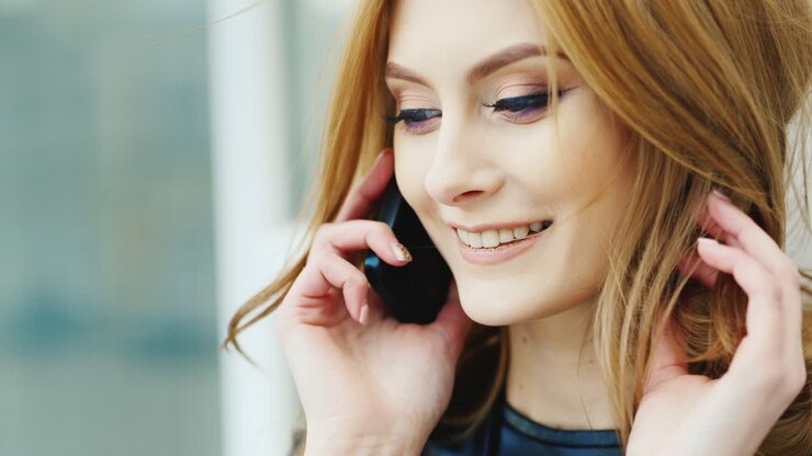 Bellissima donna con i capelli lunghi che parla al telefono all'aperto. Video HD.