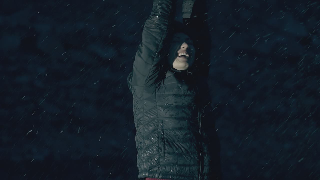 young woman in jacket gets pleasure from heavy night rain