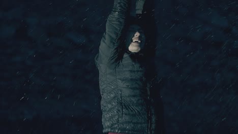 una joven con chaqueta se deleita con la fuerte lluvia nocturna.