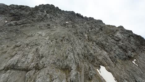 fpv drone flying close to the sharp edges of a steep mountain in tyrol region of austria