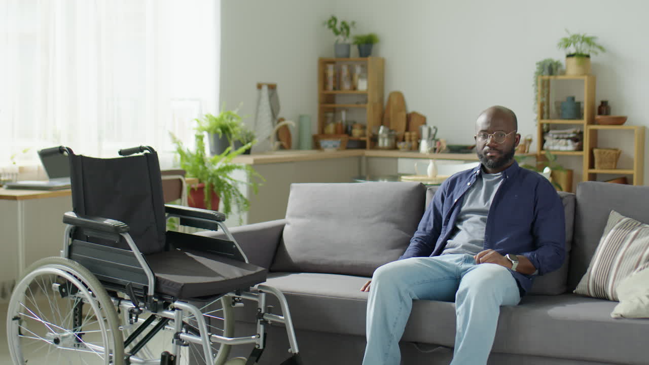 Afroamerikansk mann med funksjonshemming som poserer for kamera hjemme