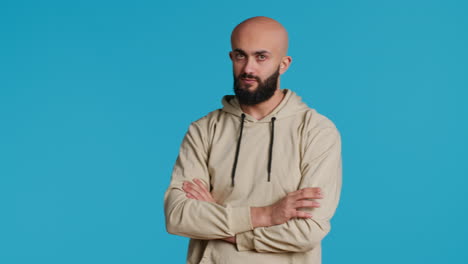 un adulto joven con una sudadera con capucha esperando algo en el estudio