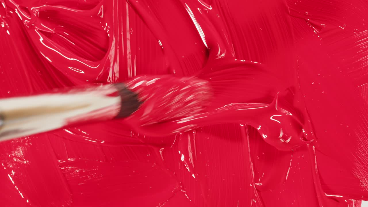Pittura rossa stesa con un pennello in primo piano