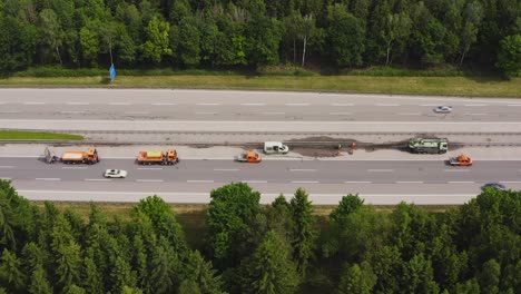 Baustelle-An-Einer-Deutschen-Autobahn-Mit-Einer-Gruppe-Von-Straßenarbeitern,-Die-Ihre-Arbeit-Erledigen,-Indem-Sie-Die-Zwischenschranke-Kontrollieren,-Die-Neben-Ihren-Lastwagen-Steht,-Während-Autos-An-Der-Wartungsstelle-Vorbeifahren