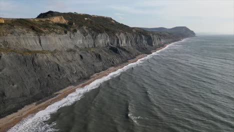 aerial-view-of-the-shoreline-in-Dorset,-England,-waves-on-the-sea